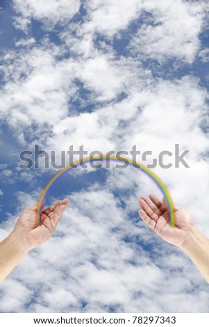 A colorful rainbow bridging a pair of hand against a dramatic cloudy blue sky.