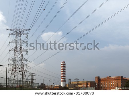 A gas fire power station with the word power on its towering chimney, and power pylon with power cable line snaking out of the station against a cloudy sky.