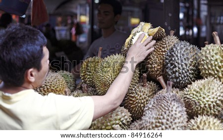 KUALA LUMPUR, MALAYSIA - SEPT 11: A shopper at a durian fruit stall on September 11, 2011 in Bazaar Baru Chow Kit, Kuala Lumpur, Malaysia. Durian is revered in Southeast Asia as the King of Fruits.