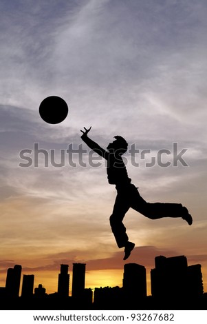 Silhouette of a sport boy throwing a basketball in an urban surrounding against a surreal candy colored sunset for the concept of urban playground.