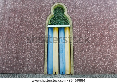 A vintage colorful decorative metal folding door with moorish motif on a grungy mosaic wall.