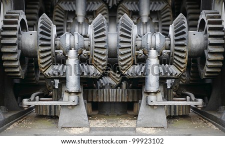 Giant mechanical cast iron gear in a congested industrial engine chamber.