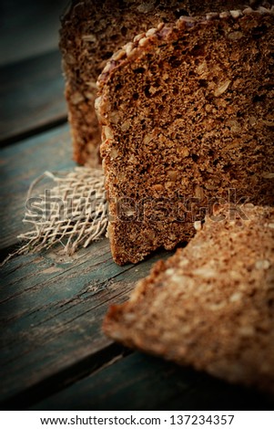 Rustic loaf of bread with sunflower seeds on wood background