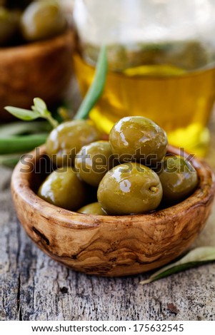 Fresh olives and olive oil  on rustic wooden background. Olives in olive wood.