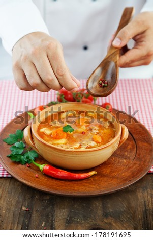 Hotel restaurant concept. Chef is finishing presenting stew dish with spices and garnish