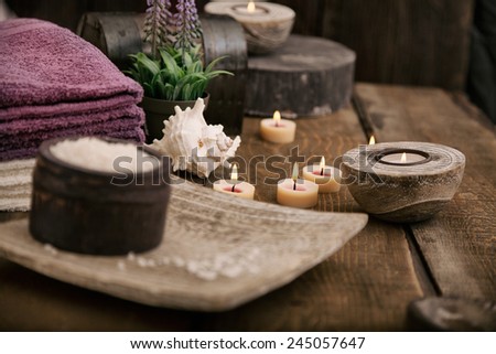 Spa and wellness setting with natural bath salt, candles, towels and flower. Wooden dayspa nature set