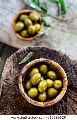 Fresh olives on rustic wooden background. Olives in olive wood.