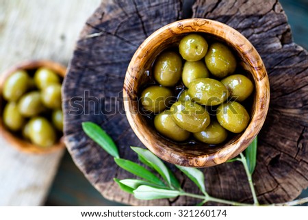 Fresh olives on rustic wooden background. Olives in olive wood.