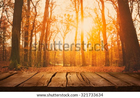 Wooden table. Autumn design with leaves falling in  forest and empty display. Space for your montage. Season fall background