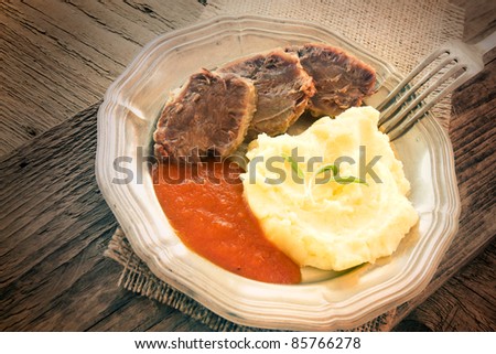 Healthy eating. Boiled beef with mashed potatoes and tomato sauce in rustic wooden setting