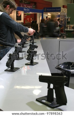 NURNBERG, GERMANY - MARCH 11: An unidentified man holds a pistol at the Glock pistols stand at IWA 2012 & OutdoorClassics exhibition on March 11, 2012 in Nurnberg, Germany