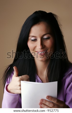 Female model showing thumbs up while reading information on white paper