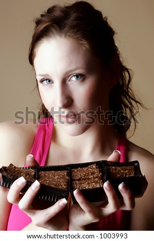 Female wearing a pink top and holding a box of chocolates with both hands