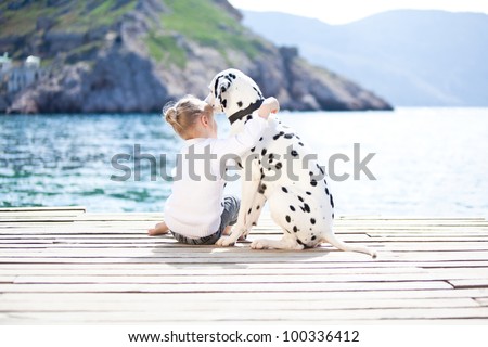 Happy baby girl with her dog on berth in summer