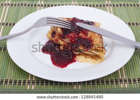 Pancake with jam - delicious and healthy dessert.  Knife and fork on a plate are