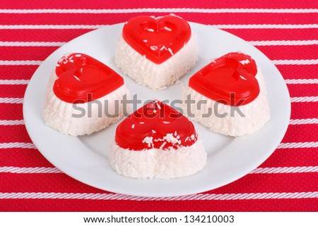 Four cheese cake in the form of heart on a white plate on a red background of a striped tablecloth