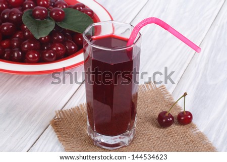 glass of cherry juice and plenty of ripe cherries on the table