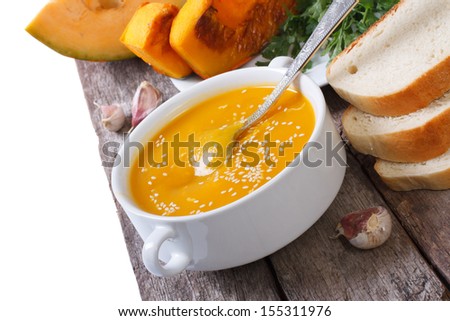 pumpkin soup with sesame seeds and bread on a wooden table