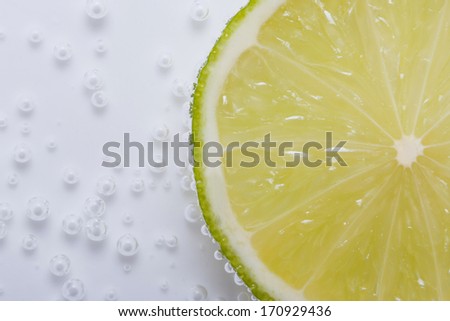 half fresh lime in water with bubbles close up