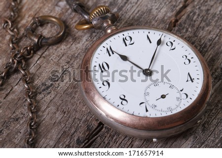 old pocket watch on a chain on an old wooden table macro