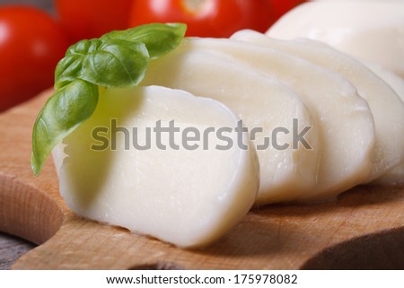 macro sliced ??mozzarella cheese with basil on kitchen board