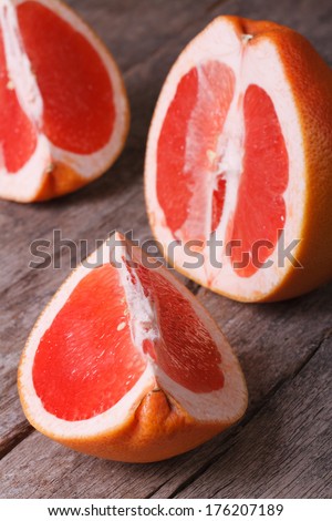 large pieces of red grapefruit on the old wooden table closeup. vertical