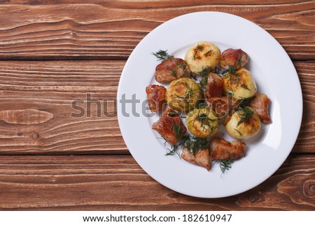 new potatoes with dill and fried slices pork on a white plate on the table. view from above. horizontal