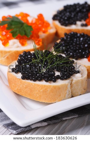 sandwiches black and red caviar on a plate closeup. vertical
