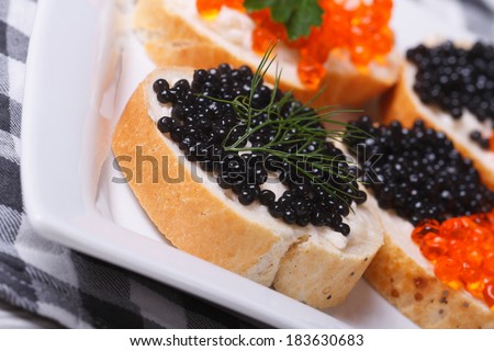 sandwiches with black and red caviar on a plate macro. horizontal