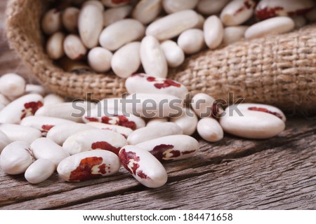 White kidney beans with red spots pours out of the bag on the table close-up. horizontal