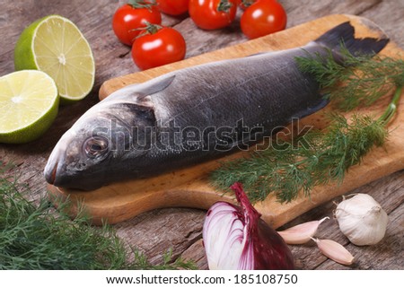 Fresh raw fish sea bass on a cutting board with vegetables closeup