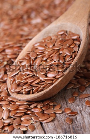 Flax seeds in a wooden spoon macro on a table. Vertical