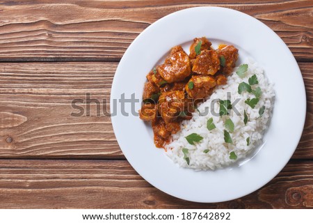Rice with chicken in curry sauce and herbs on a plate with a horizontal top view.