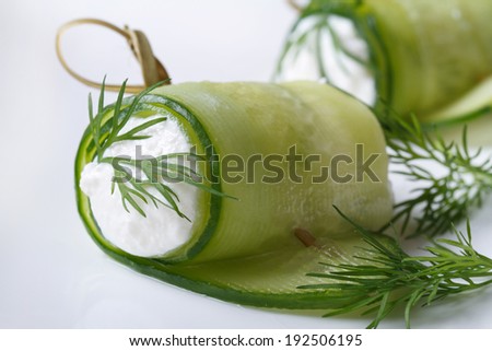 appetizer of cucumber rolls with cream cheese and dill on white plate macro. horizontal