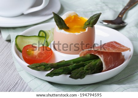 Boiled egg with green asparagus, ham and vegetables closeup. horizontal