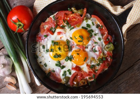 Fried eggs with vegetables on a frying pan and the ingredients on the table horizontal close-up view from above