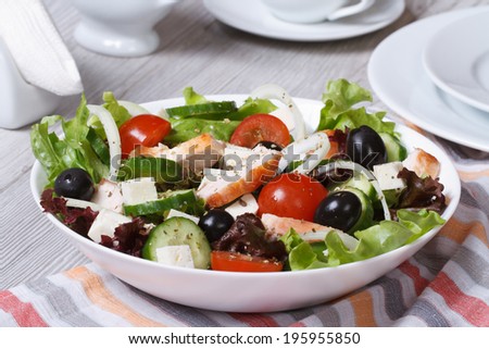 Salad with chicken, tomatoes, cucumbers, onions and cheese on the table.