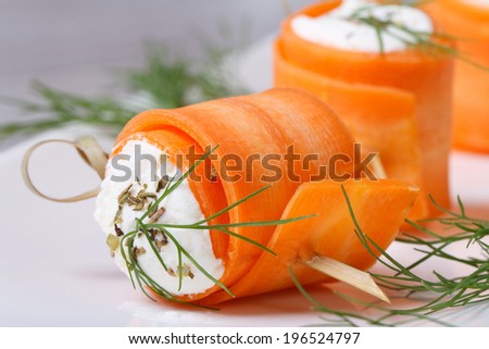 Gourmet rolls of young carrots with cream cheese and dill macro on a white plate. horizontal