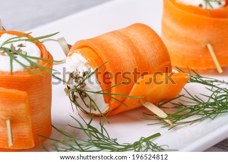 Rolls of young carrots with cottage cheese and dill macro on a white plate. horizontal