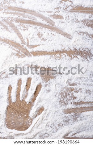female palm print on flour scattered on the kitchen board. vertical background closeup