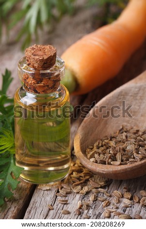 The essential oil of carrot seeds in a glass bottle on a wooden table. vertical macro