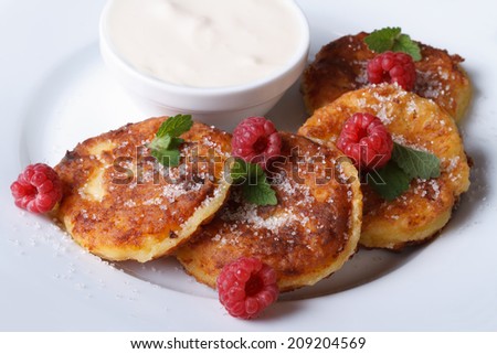 Cheese pancakes with raspberries and sour cream on a white plate closeup. a horizontal top view