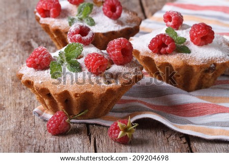 raspberry cupcakes with mint, sprinkled with powdered sugar closeup on wooden table horizontal