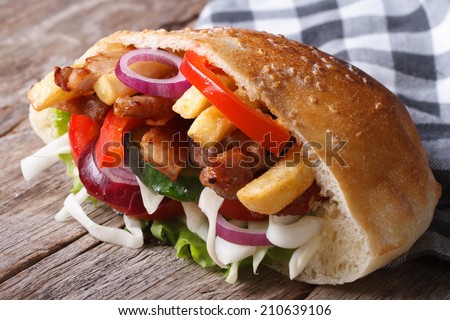 Doner kebab with meat, vegetables and fries in pita bread close-up on a napkin horizontal