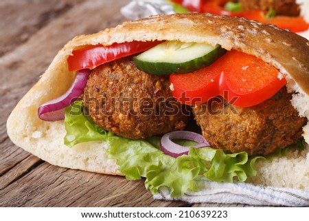 falafel with fresh vegetables in pita bread close-up on wooden table horizontal