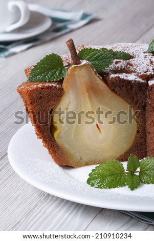 Slice of chocolate cake with whole pears and mint closeup on a white plate on the table vertical