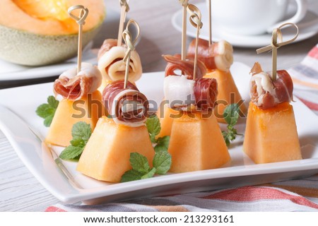 Italian appetizer: melon with ham on skewers on a plate close up. horizontal