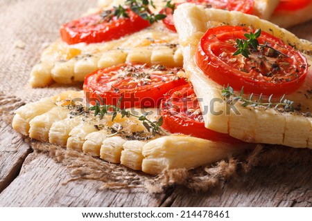 Traditional puff pastry with tomatoes, cheese and herbs closeup on the table. horizontal