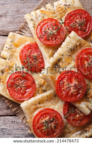 Puff pastry with tomato and cheese on the table close-up vertical. top view