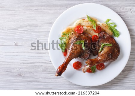 duck legs baked with apples and tomatoes on white plate close-up view from above. horizontal